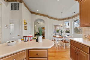 Kitchen featuring light wood-type flooring, arched walkways, light countertops, and pendant lighting