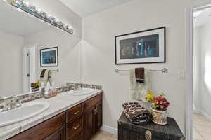 Bathroom with tile patterned flooring, a sink, baseboards, and double vanity