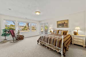 Carpeted bedroom featuring a textured ceiling and baseboards