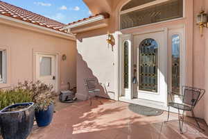 Entrance to property featuring stucco siding, a tile roof, and a patio