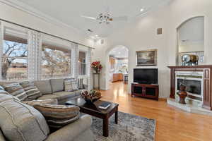 Living room with visible vents, arched walkways, a premium fireplace, ornamental molding, and light wood-style floors