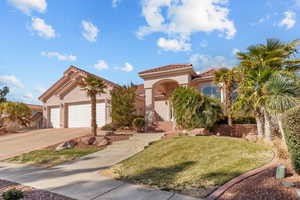 Mediterranean / spanish-style home featuring stucco siding, an attached garage, a front yard, driveway, and a tiled roof