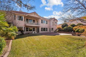 Back of property featuring a balcony, a tiled roof, a lawn, stucco siding, and a patio area