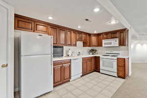 Kitchen with white appliances, visible vents, light countertops, a sink, and recessed lighting