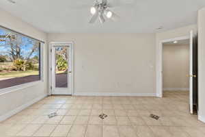 Interior space featuring light tile patterned floors, a ceiling fan, and baseboards