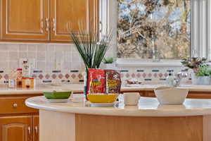 Interior space with light countertops, brown cabinetry, and backsplash