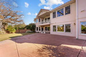 Rear view of house with ceiling fan, a patio, a balcony, a yard, and stucco siding