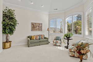 Sitting room with a healthy amount of sunlight, carpet, visible vents, and crown molding