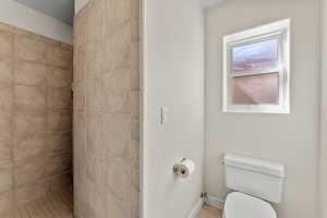 Bathroom featuring a tile shower and toilet