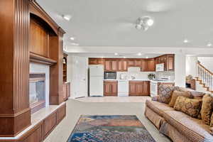 Living room featuring light carpet, a textured ceiling, a tiled fireplace, and stairs