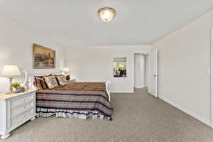 Bedroom with a textured ceiling, carpet floors, and baseboards