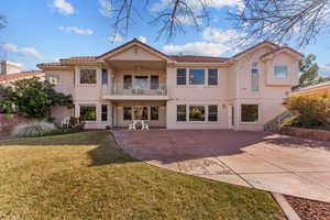 Rear view of property with a patio, stucco siding, a lawn, a ceiling fan, and a balcony