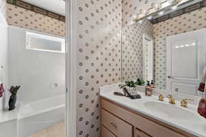 Full bathroom with tile patterned flooring, vanity, and wallpapered walls