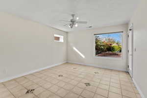 Unfurnished room featuring visible vents, a textured ceiling, baseboards, and a ceiling fan