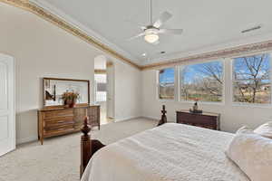 Bedroom with ornamental molding, arched walkways, light carpet, and baseboards