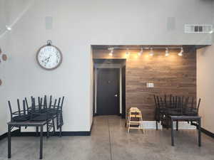 Dining room with visible vents, concrete floors, wooden walls, and baseboards