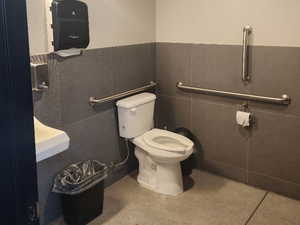 Bathroom featuring tile patterned flooring, toilet, a wainscoted wall, visible vents, and tile walls