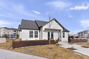 View of front of home with a fenced front yard, a shingled roof, and board and batten siding