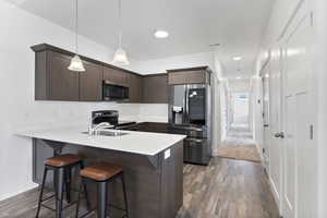 Kitchen featuring stainless steel appliances, a peninsula, light countertops, and pendant lighting