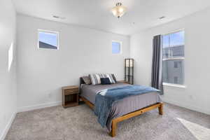 Bedroom featuring multiple windows, visible vents, and light colored carpet