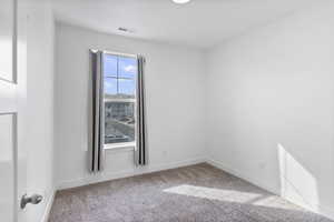 Unfurnished room featuring carpet floors, baseboards, and visible vents