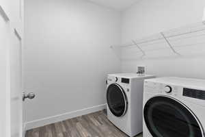 Washroom featuring dark wood-type flooring, laundry area, washer and clothes dryer, and baseboards