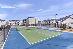 View of tennis court featuring fence and a residential view