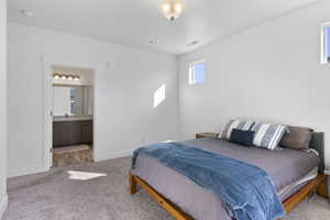 Bedroom featuring light carpet, baseboards, visible vents, ensuite bath, and a sink