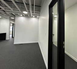 Basement with baseboards and dark carpet