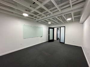 Spare room with dark carpet and baseboards