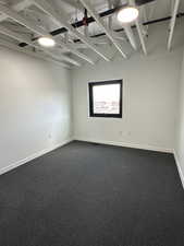 Unfurnished room with dark carpet and baseboards