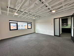 Unfurnished room featuring baseboards and dark colored carpet