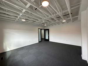 Empty room featuring dark carpet, visible vents, and baseboards