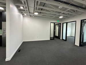Empty room featuring baseboards, visible vents, and dark colored carpet