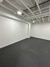 Basement featuring dark carpet and baseboards