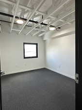 Empty room featuring baseboards and dark carpet