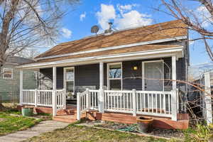 View of front of property with a shingled roof and a porch