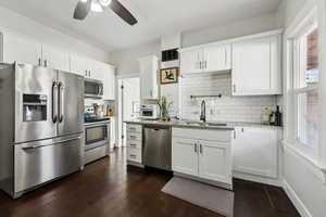 Kitchen with light stone countertops, white cabinetry, appliances with stainless steel finishes, and a sink