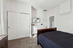 Bedroom with a closet, visible vents, and light colored carpet