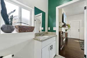 Half bath with wood finished floors and vanity