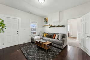 Living area featuring visible vents, wainscoting, dark wood-type flooring, baseboard heating, and a textured ceiling