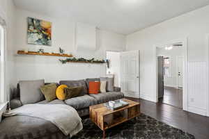 Living room with dark wood-style floors and a wainscoted wall