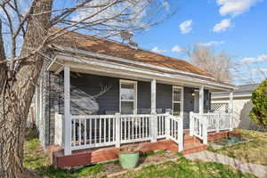 View of front of house featuring a shingled roof and covered porch