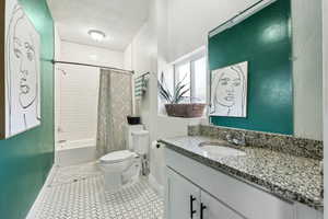 Bathroom with baseboards, vanity, toilet, and shower / bath combo with shower curtain