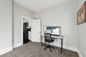 Office space with baseboards and dark carpet