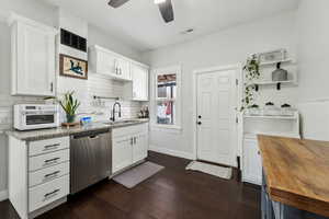 Kitchen with light stone counters, white cabinets, visible vents, and stainless steel dishwasher