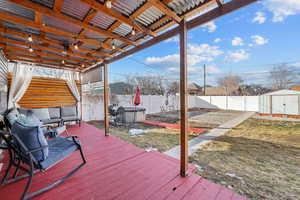 Wooden deck featuring a storage unit, an outdoor structure, and a fenced backyard