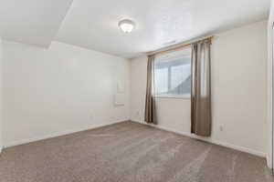 Spare room featuring carpet, visible vents, baseboards, and a textured ceiling