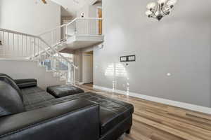 Living room with stairs, a chandelier, wood finished floors, and baseboards