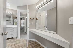 Bathroom featuring a skylight, wood finished floors, vanity, and baseboards